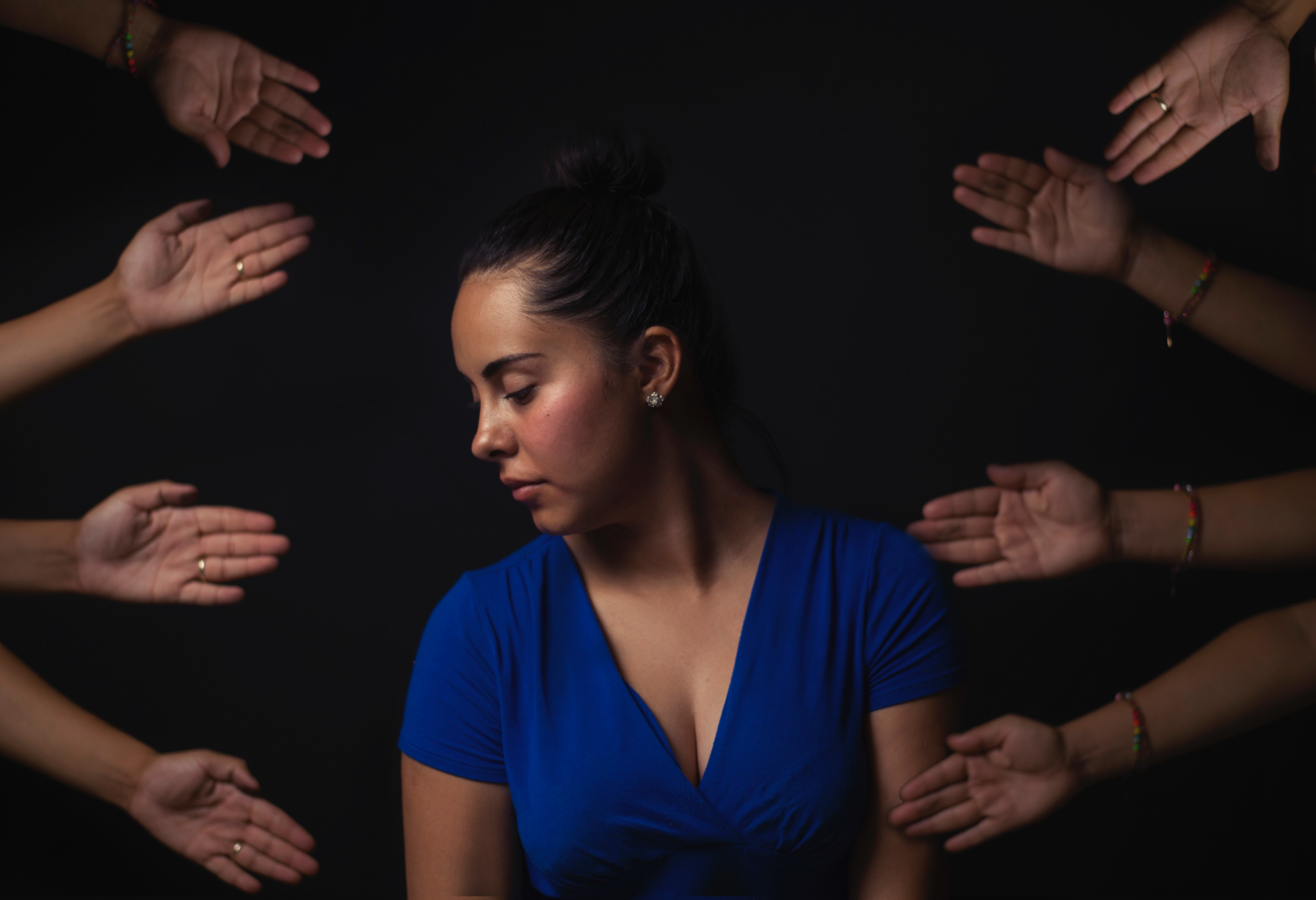 image of a sad woman, surrounded by hands reaching out to help her